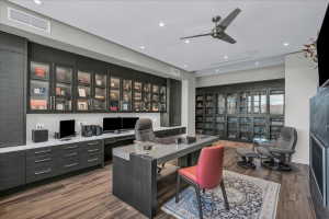 Dedicated office space featuring extensive built-in cabinetry with glass-front uppers and task lighting