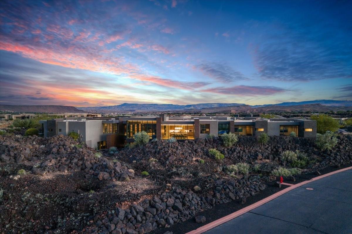 Modern desert residence featuring expansive glass windows, flat rooflines, and a stucco exterior
