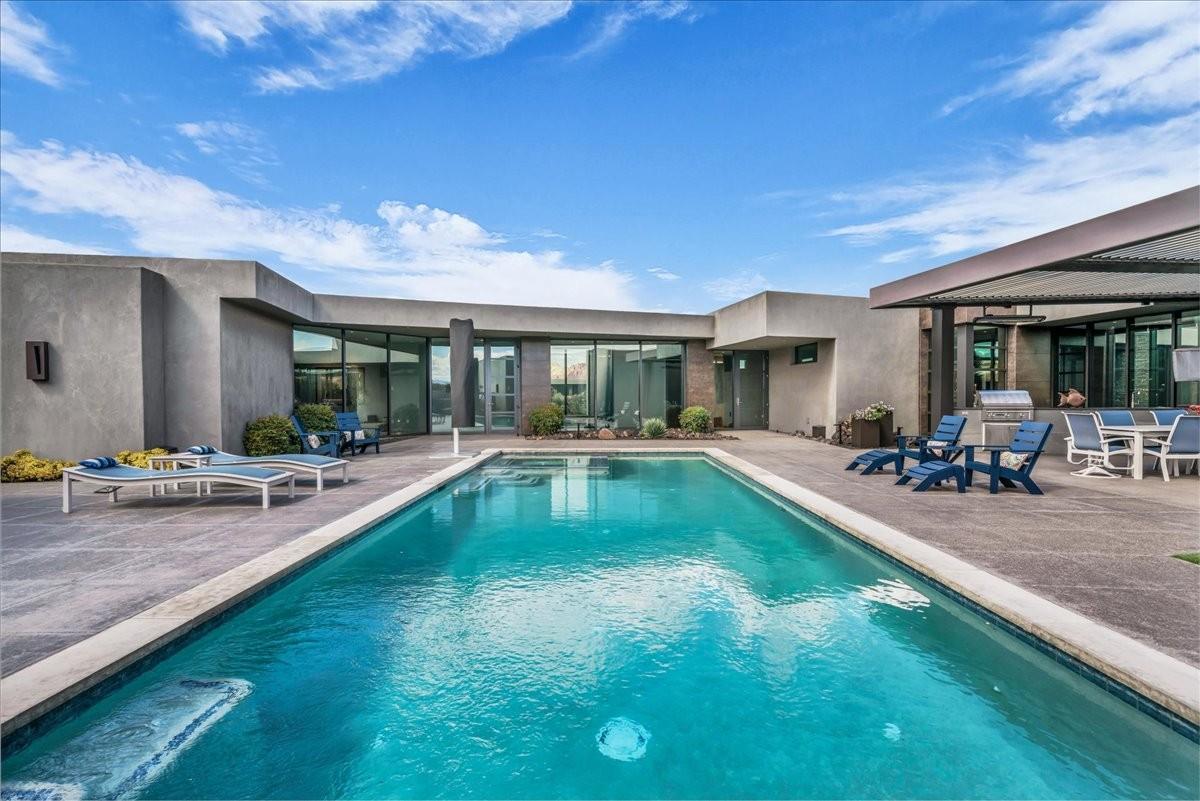 Expansive rectangular swimming pool with integrated spa, surrounded by a spacious concrete patio