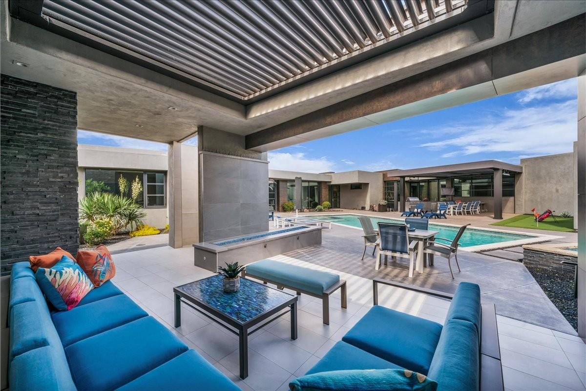 Covered patio area featuring a slatted pergola, stone veneer accent wall, and tiled flooring