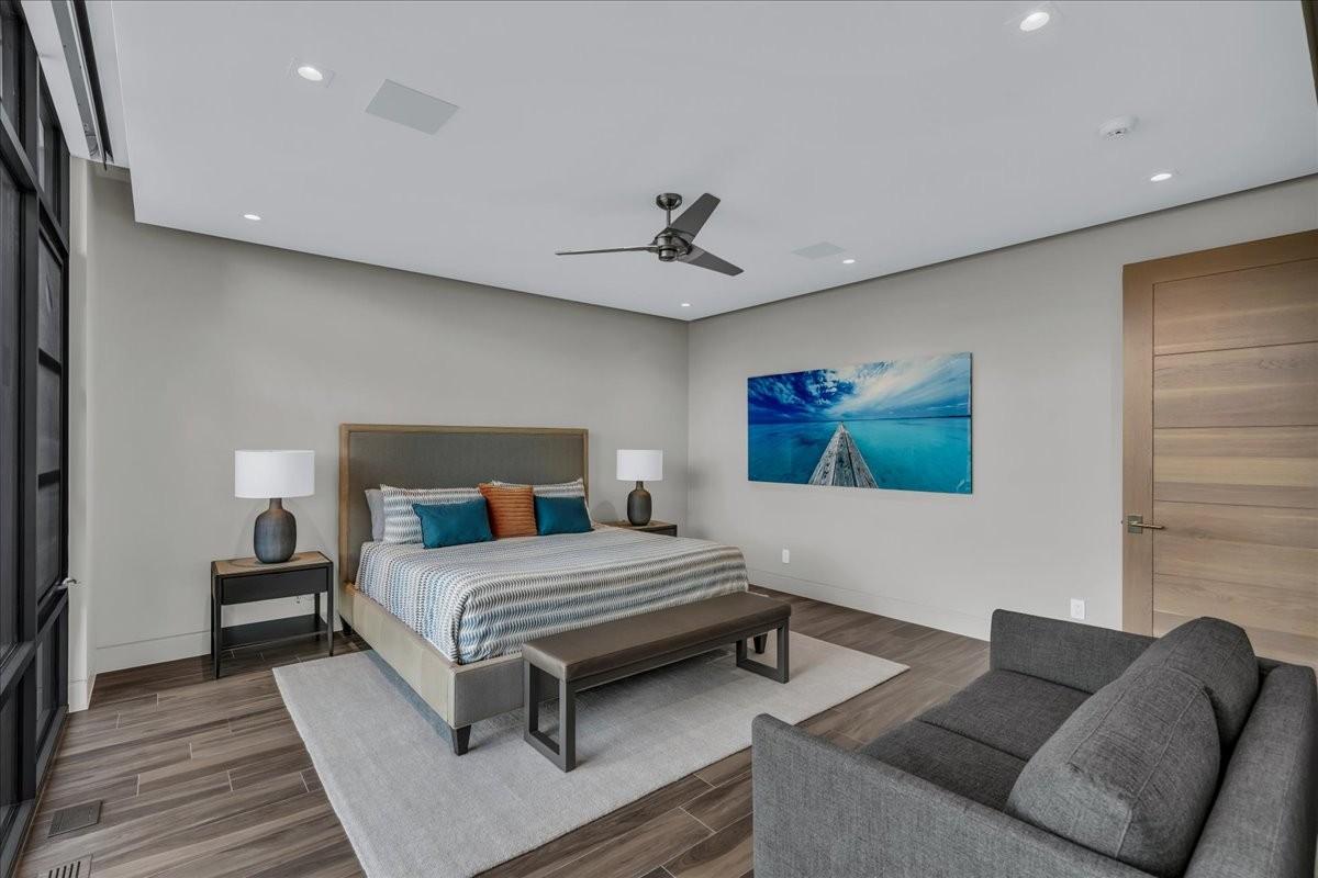 Spacious bedroom featuring wood-finish flooring, a contemporary ceiling fan, recessed lighting, and a paneled interior door