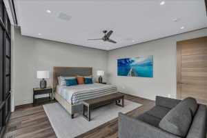 Spacious bedroom featuring wood-finish flooring, a contemporary ceiling fan, recessed lighting, and a paneled interior door