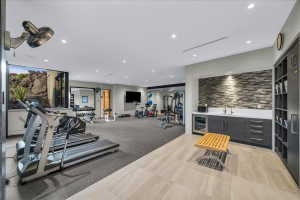 Dedicated fitness room featuring recessed lighting, a rock wall backdrop, a built-in wet bar with a beverage cooler, and a built-in storage system