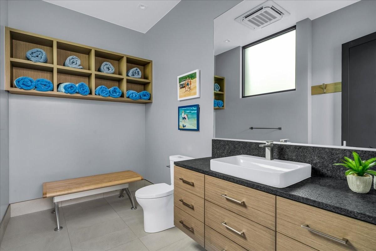Modern bathroom featuring a wood-finish vanity with a rectangular vessel sink and dark stone countertop