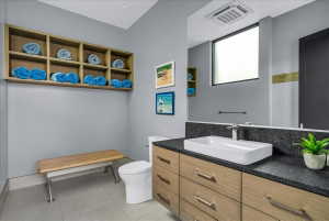 Modern bathroom featuring a wood-finish vanity with a rectangular vessel sink and dark stone countertop