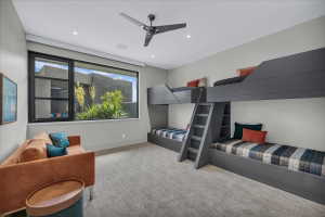 Spacious room featuring a large window overlooking exterior landscaping, built-in bunk beds with integrated ladders and shelving, recessed lighting, and a ceiling fan