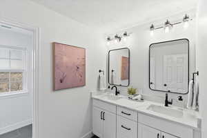 Dual vanity featuring white shaker cabinetry, white countertops, undermount sinks, and matte black fixtures