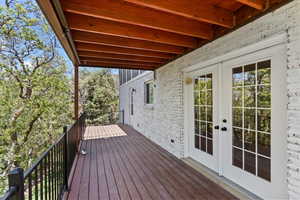 Expansive outdoor deck featuring wood-finish flooring, black metal railings, and a natural wood-plank ceiling