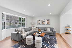 Bright living space featuring a large bay window, recessed lighting, light wood-finish flooring, and a broad arched entry