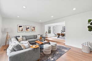Open concept living area featuring light wood-finish flooring, recessed lighting, and a broad entry to a raised dining area