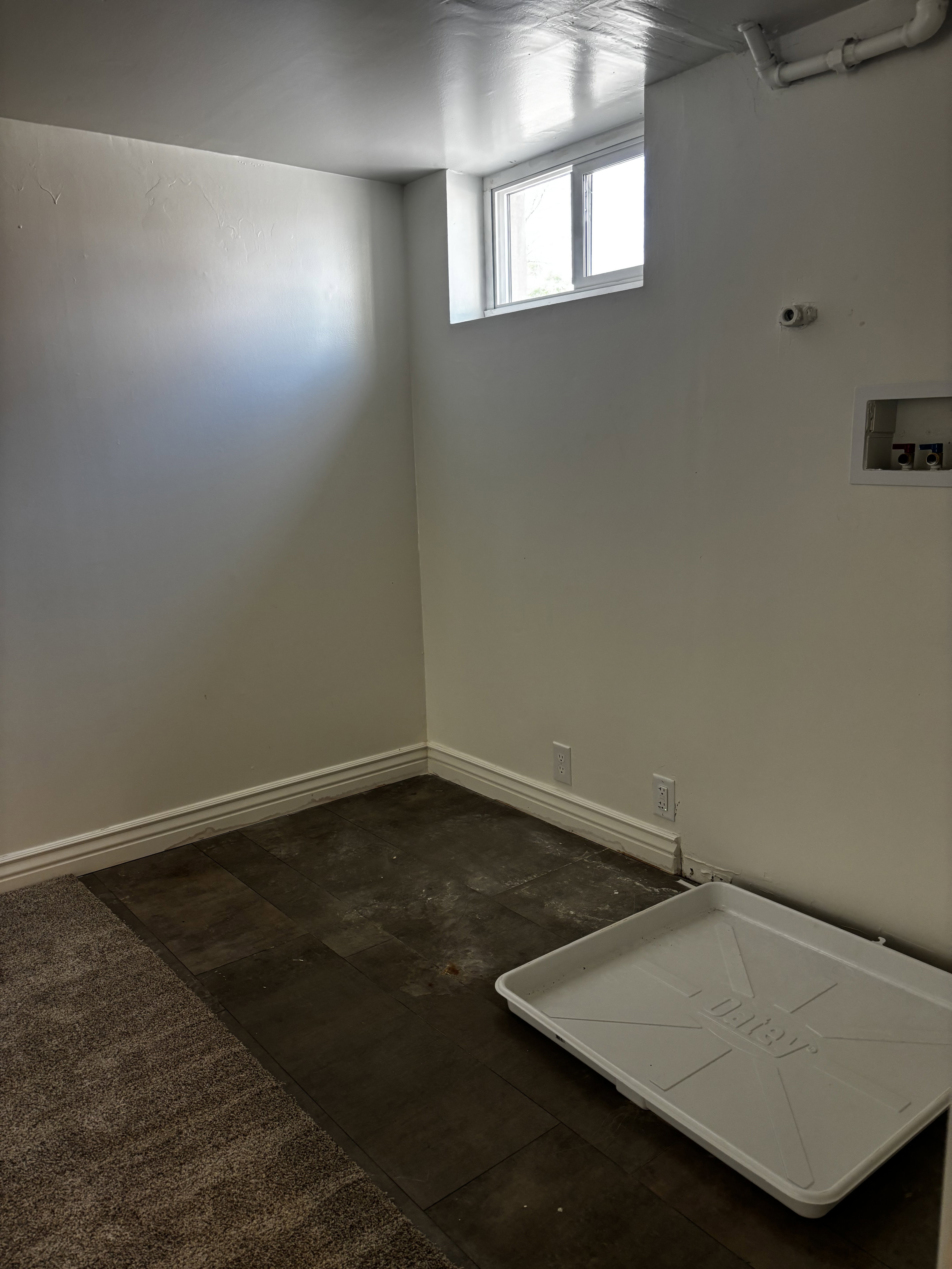 Room featuring a window, painted walls, baseboards, and mixed flooring with carpet and wood-finish sections