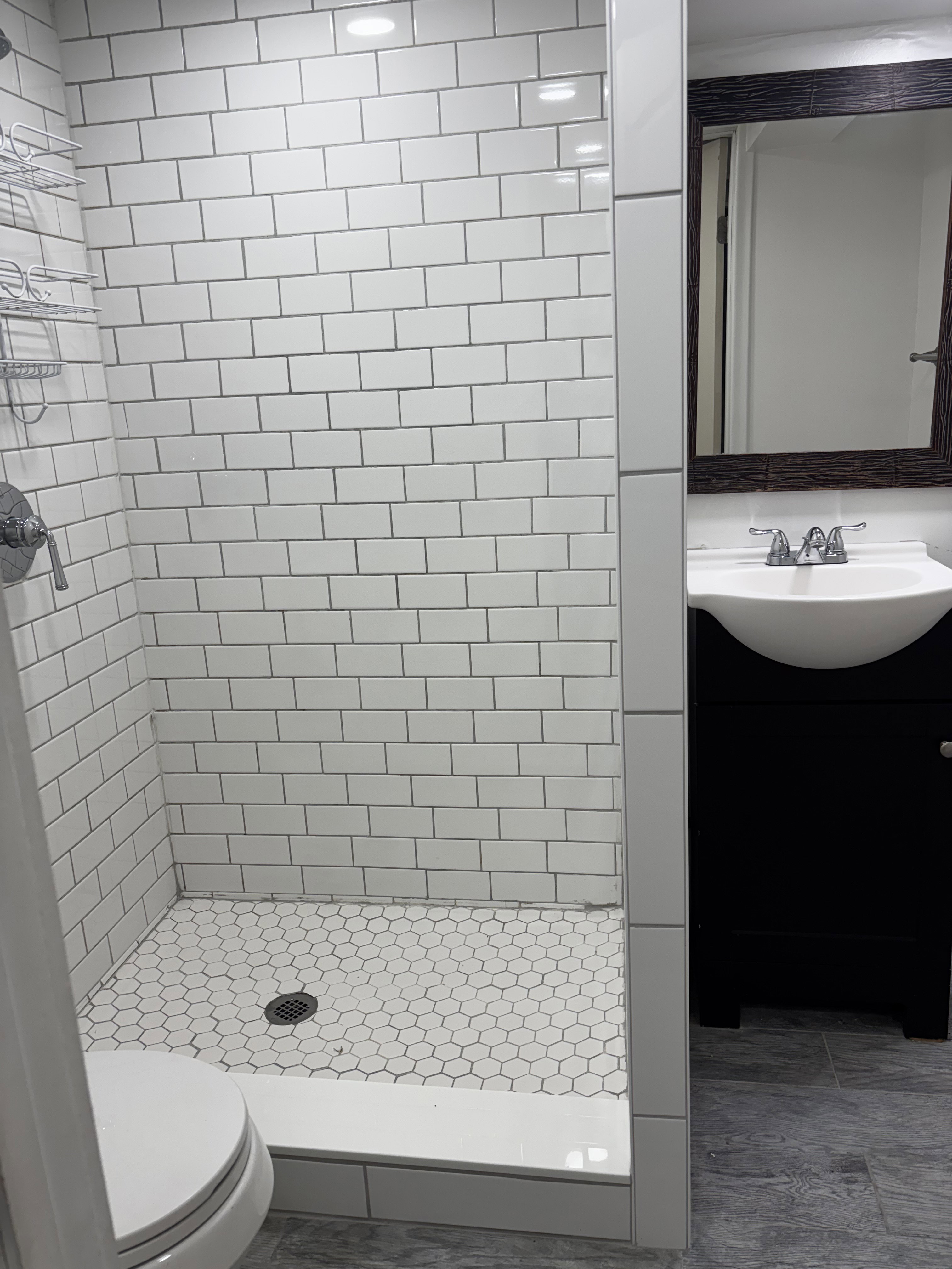 Bathroom featuring a shower with white subway tile walls and a hexagonal tile floor