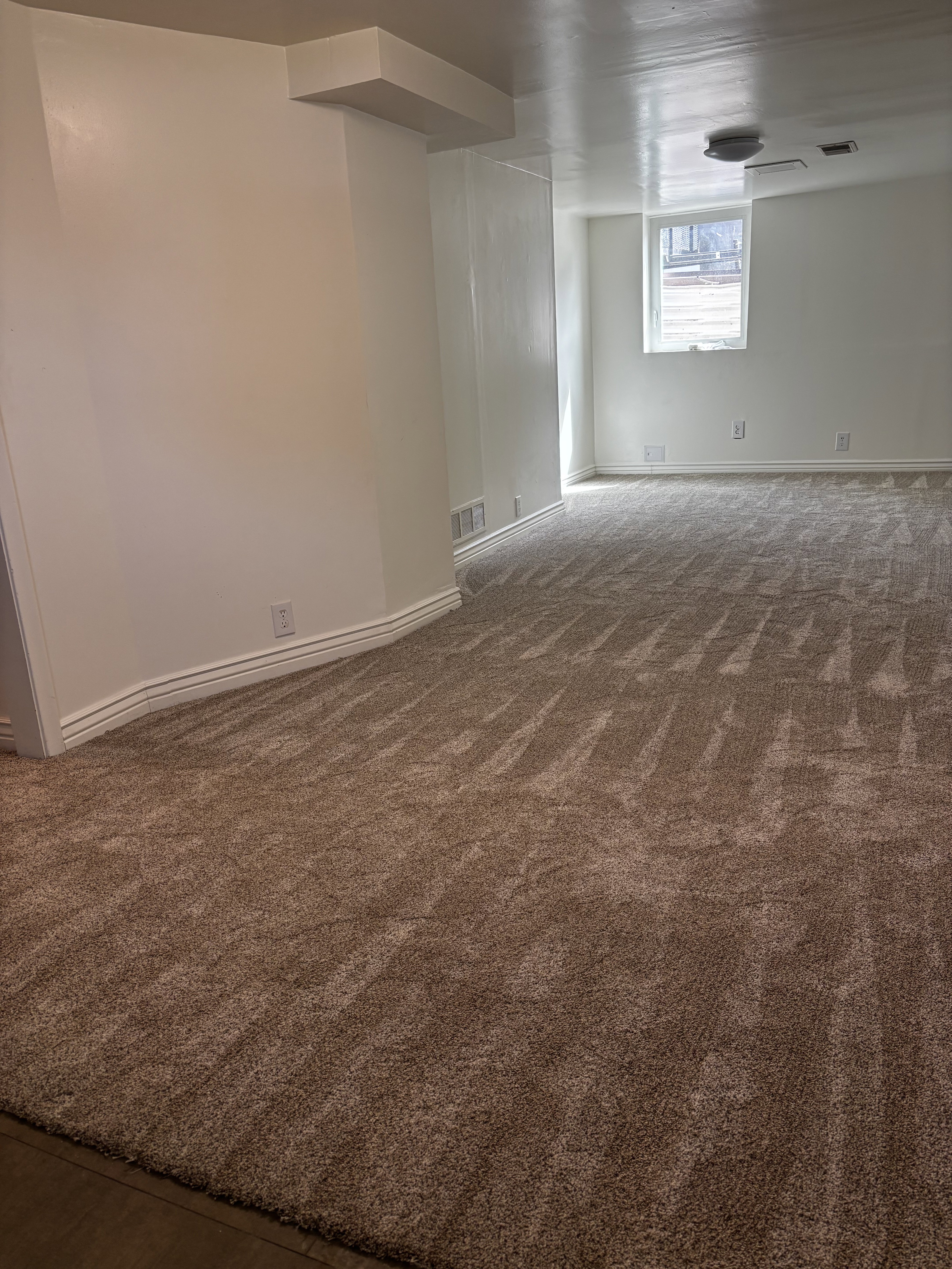 Room featuring a neutral wall color, built-in ceiling lighting, a window, baseboard trim, and a patterned carpet