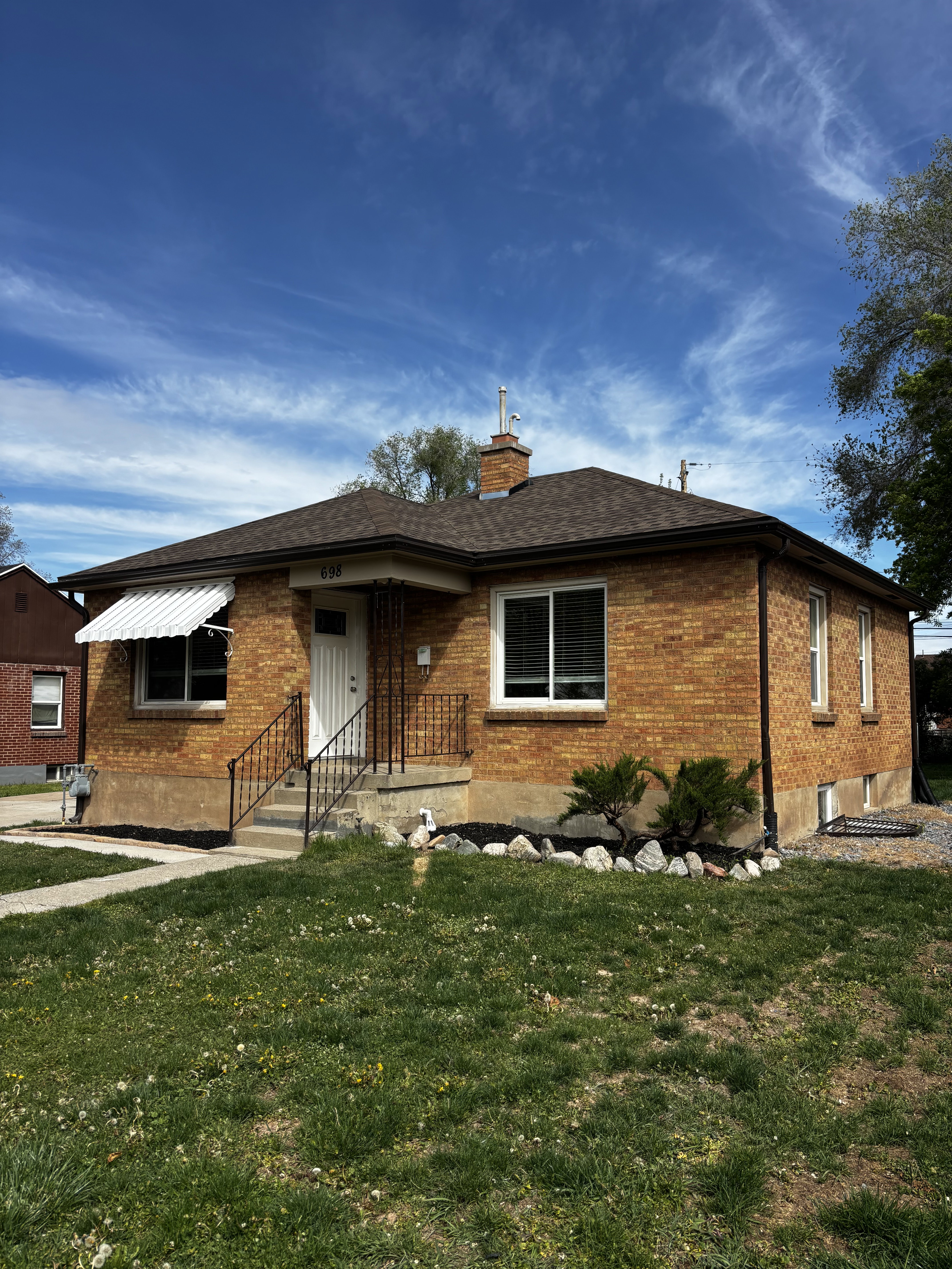 Brick exterior property with a dark shingle roof and white trim windows