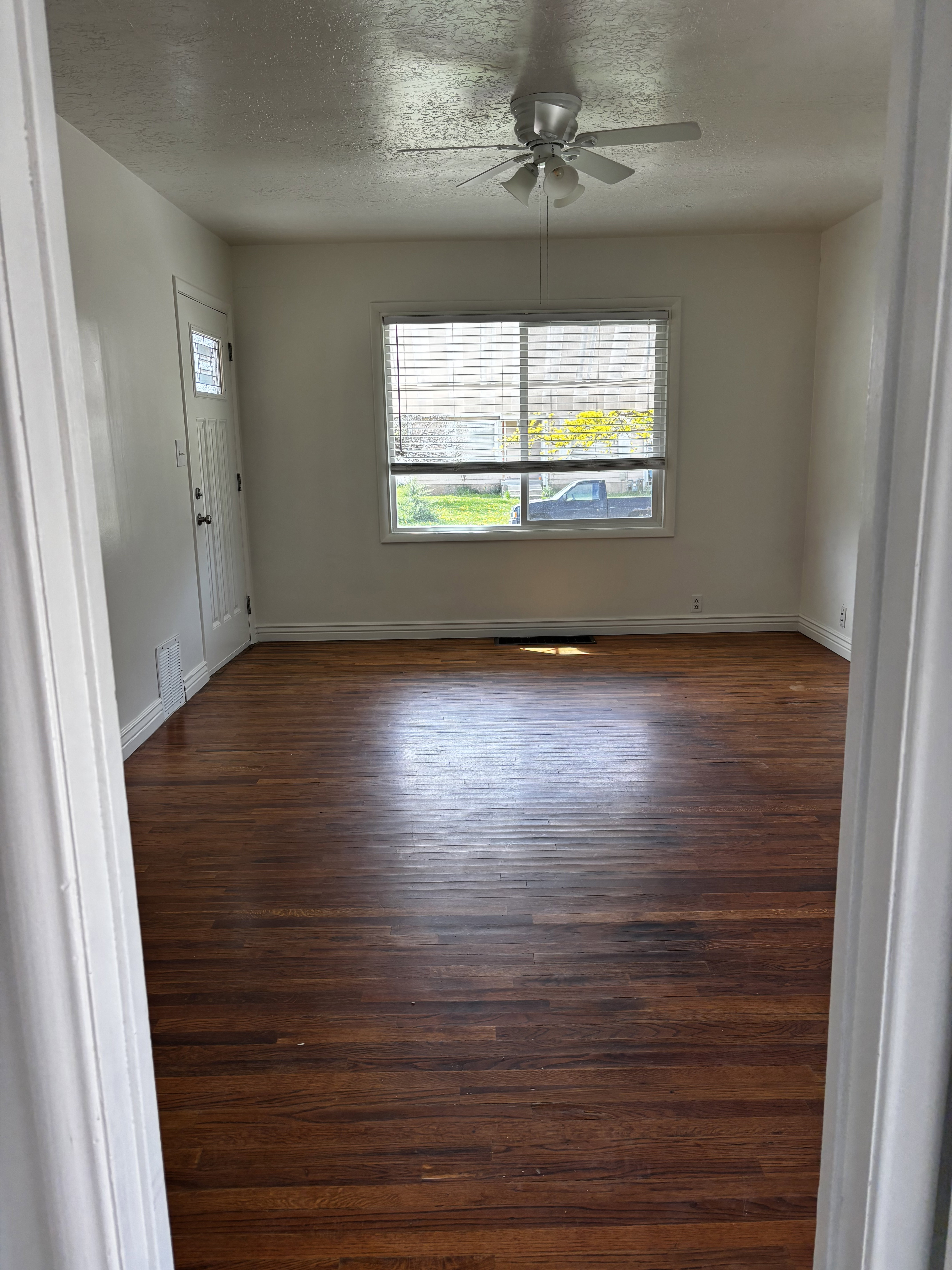 Wood-finish flooring throughout, featuring a white ceiling fan with integrated lighting