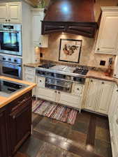 Gourmet kitchen featuring a professional-grade stainless steel gas range with a custom wood-paneled hood