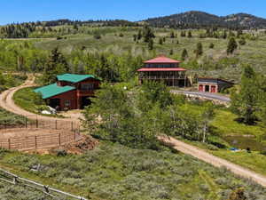 Expansive property featuring two distinct structures, a round pen, and a pond