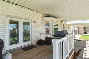 Covered patio with wood-finish decking and white vinyl siding