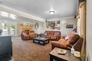 Spacious living area featuring neutral carpeting, a stone-surround fireplace, and crown molding