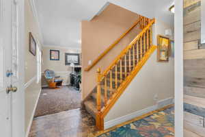 Entry/foyer featuring a wood-finish staircase with carpeted treads and a detailed balustrade