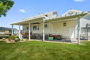 Expansive backyard featuring a manicured lawn, an extended patio with a pergola, and a multi-level deck with white railings