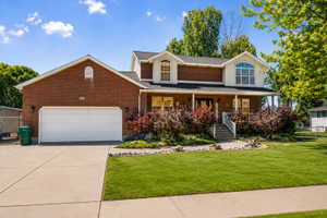 Traditional two-story residence featuring brick facade, a two-car garage & covered front porch