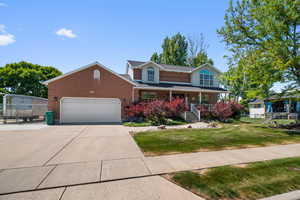 Two-story residence featuring a brick facade with a columned front porch and a two-car garage