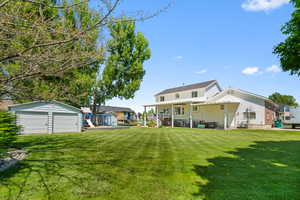 Expansive green lawn with a detached two-car shop and covered deck & patio