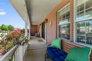 Covered front porch featuring a concrete surface, white railings, and brick exterior