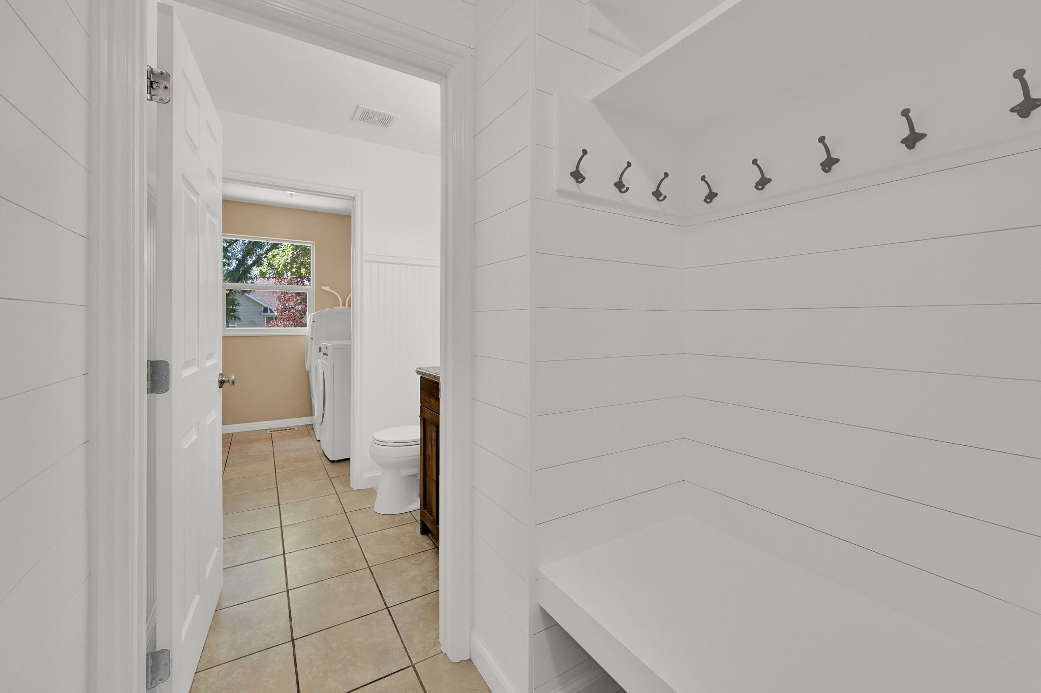 Mudroom area featuring white shiplap walls, a built-in bench, and coat hooks