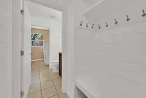 Mudroom area featuring white shiplap walls, a built-in bench, and coat hooks