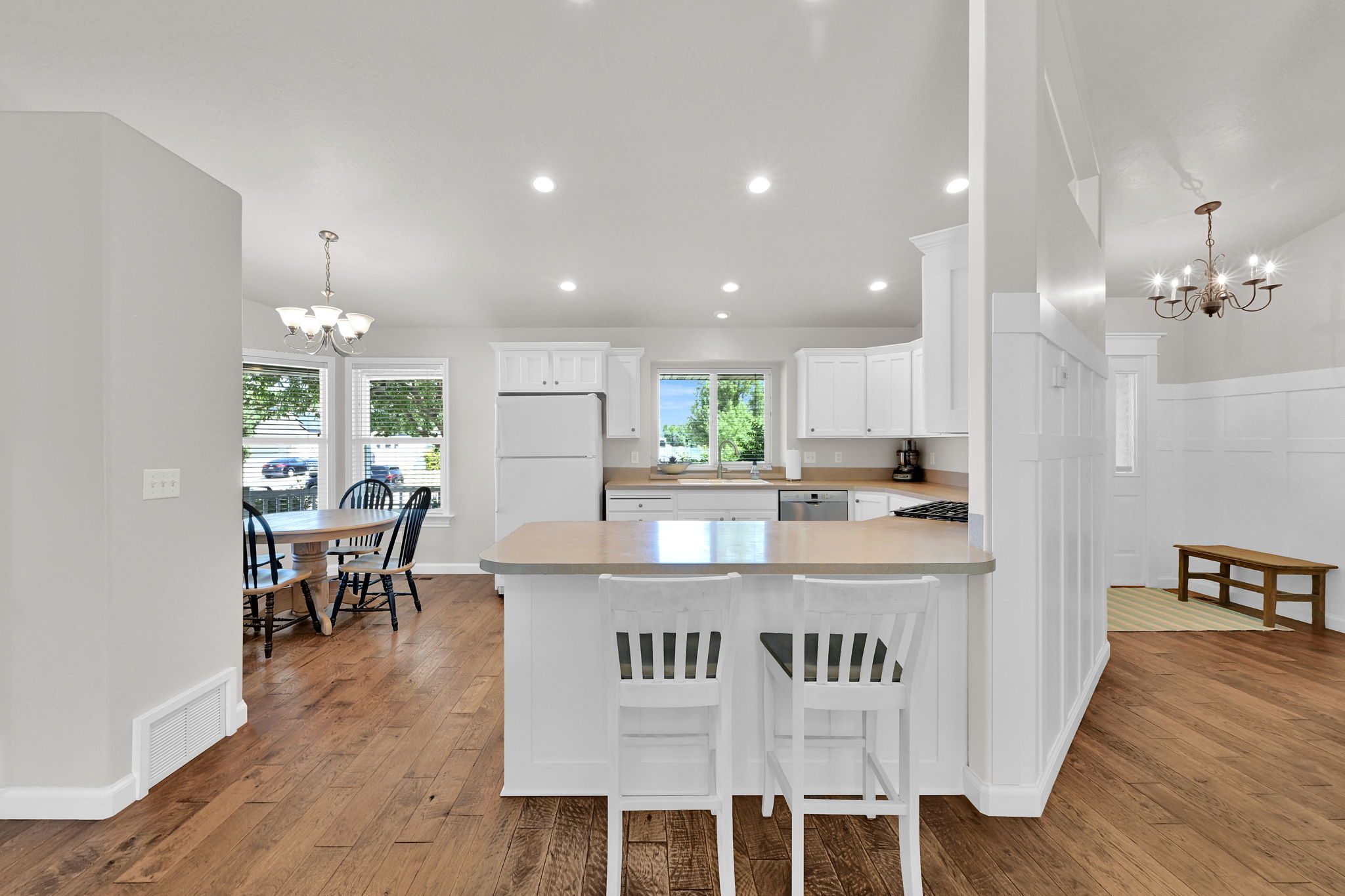 Open-concept kitchen featuring white cabinetry, light-toned countertops, and recessed lighting
