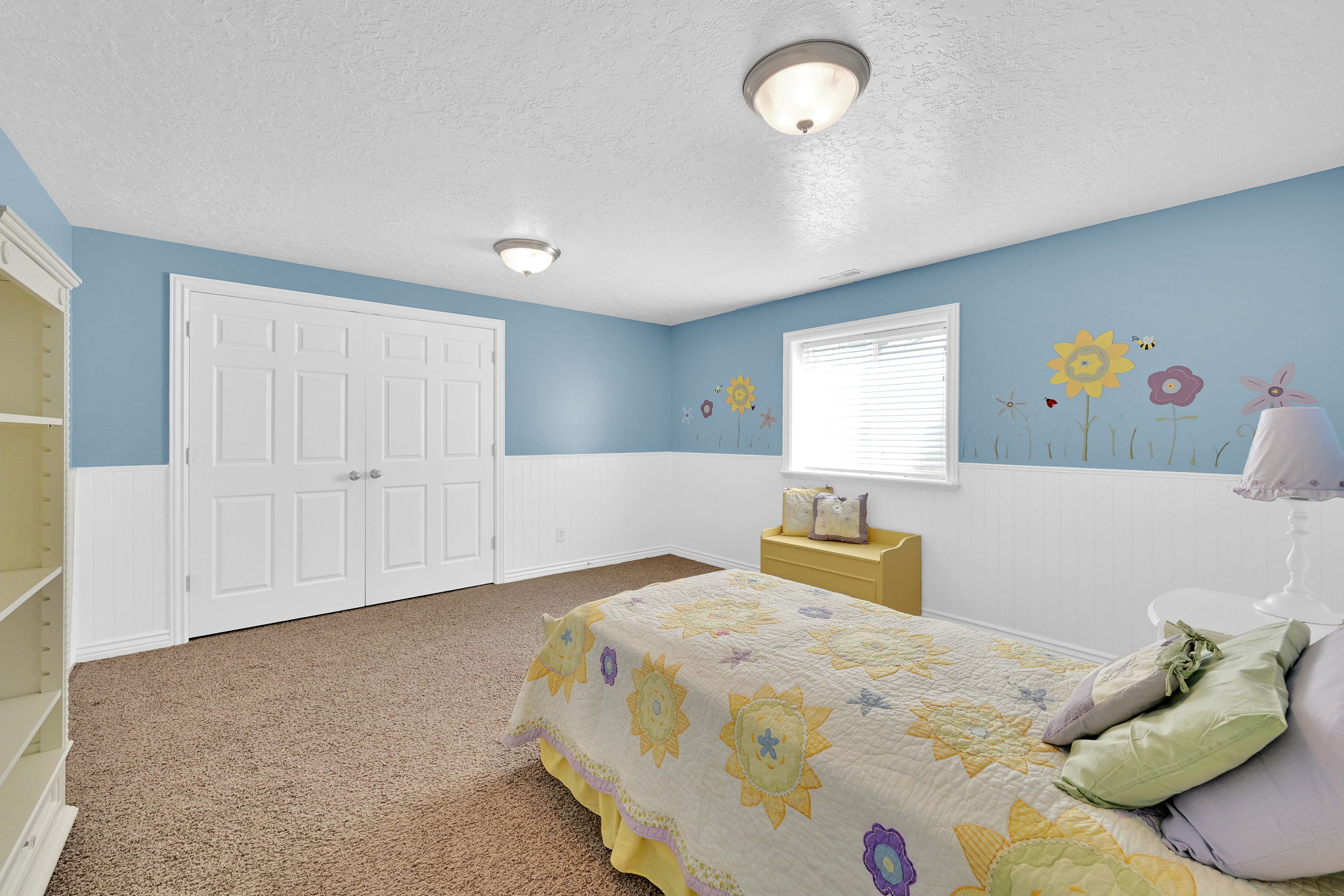 Expansive room featuring durable carpet flooring, two-panel bifold closet doors, and wainscoting paneling
