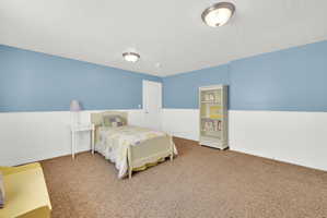 Spacious room featuring light blue walls with white wainscoting, brown carpet flooring, and white trim
