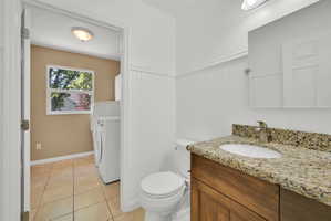 Bathroom featuring a wood-finish vanity with a stone countertop and an oval undermount sink