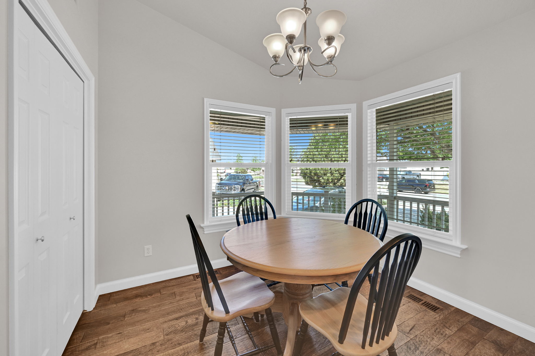 Dining area featuring a bay window, wood-finish flooring, a contemporary chandelier, and a white bi-fold closet
