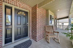 Inviting entry featuring a black paneled door with an arched decorative glass insert, complemented by a sidelight and brick facade