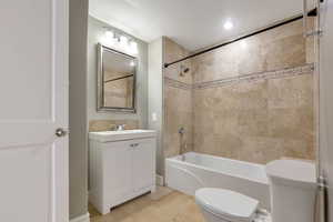 Bathroom featuring a tub/shower combination with full-height tile surround and decorative accent band