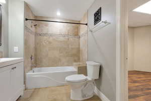 Bathroom featuring a white bathtub with chrome fixtures, full-height tiled walls, and a decorative mosaic accent band