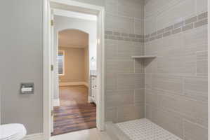 Walk-in shower with horizontal gray tile, decorative mosaic tile band, and built-in corner shelf