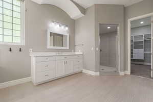 Spacious bathroom featuring a double vanity with ample storage, a glass-enclosed shower, and light-toned tile flooring