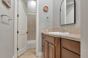 Bathroom vanity featuring an integrated sink, brushed nickel faucet, and a light-toned countertop with a tiled backsplash