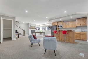 Spacious recreation room featuring a built-in wet bar with wood cabinetry and stone countertops