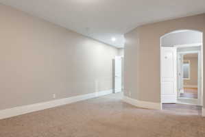 Spacious room featuring neutral carpeting, light neutral walls, white baseboards, and recessed lighting