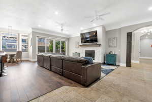 Spacious living area featuring wood-finish flooring, a contemporary fireplace with a stone surround and wood mantel, and expansive glass sliding doors