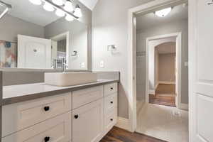 Vanity featuring white shaker cabinetry, a vessel sink, and a light-toned countertop