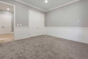 Room featuring neutral grey walls with white wainscoting and crown molding