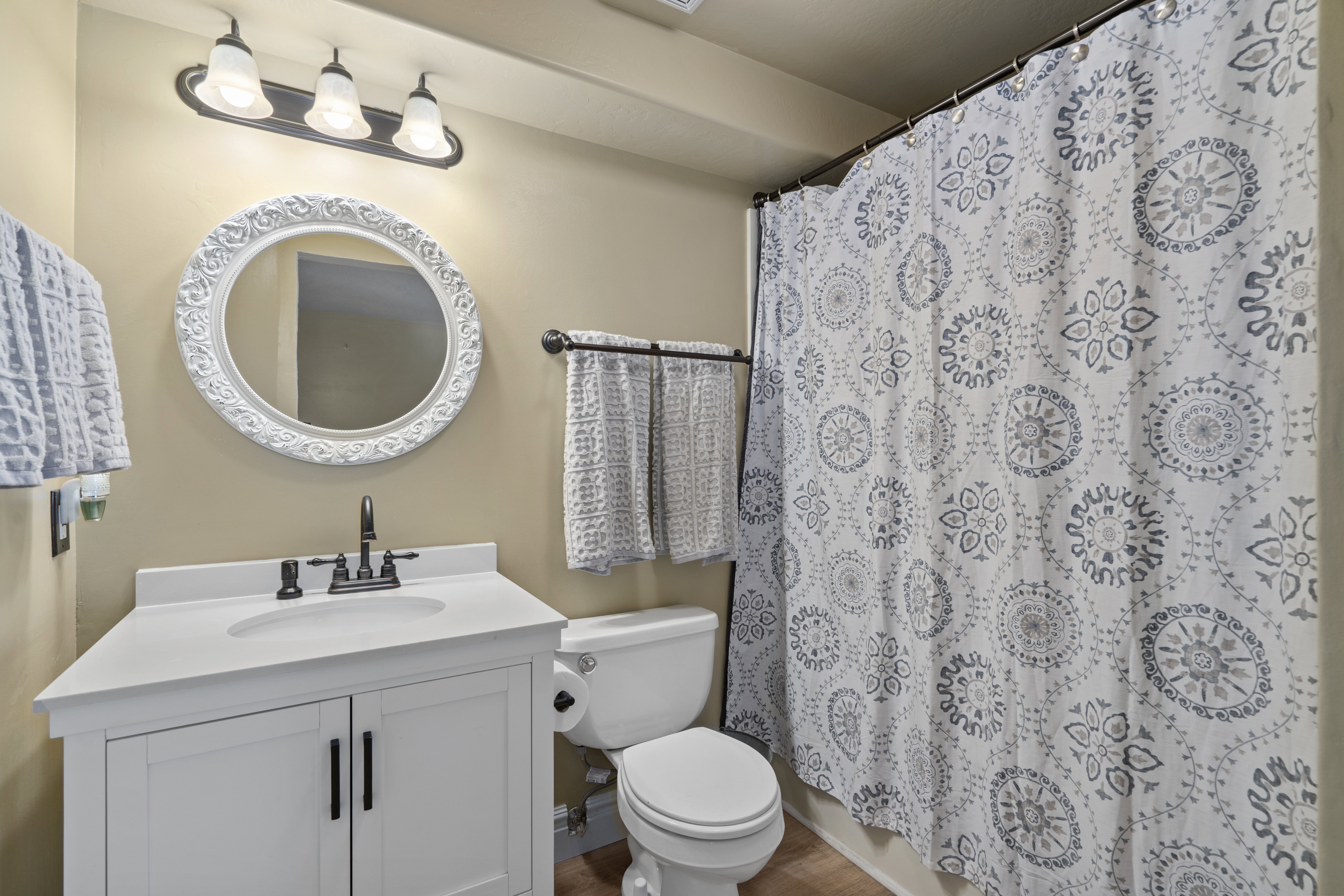 Bathroom featuring a white vanity with integrated sink, black faucet, and an ornate white framed mirror
