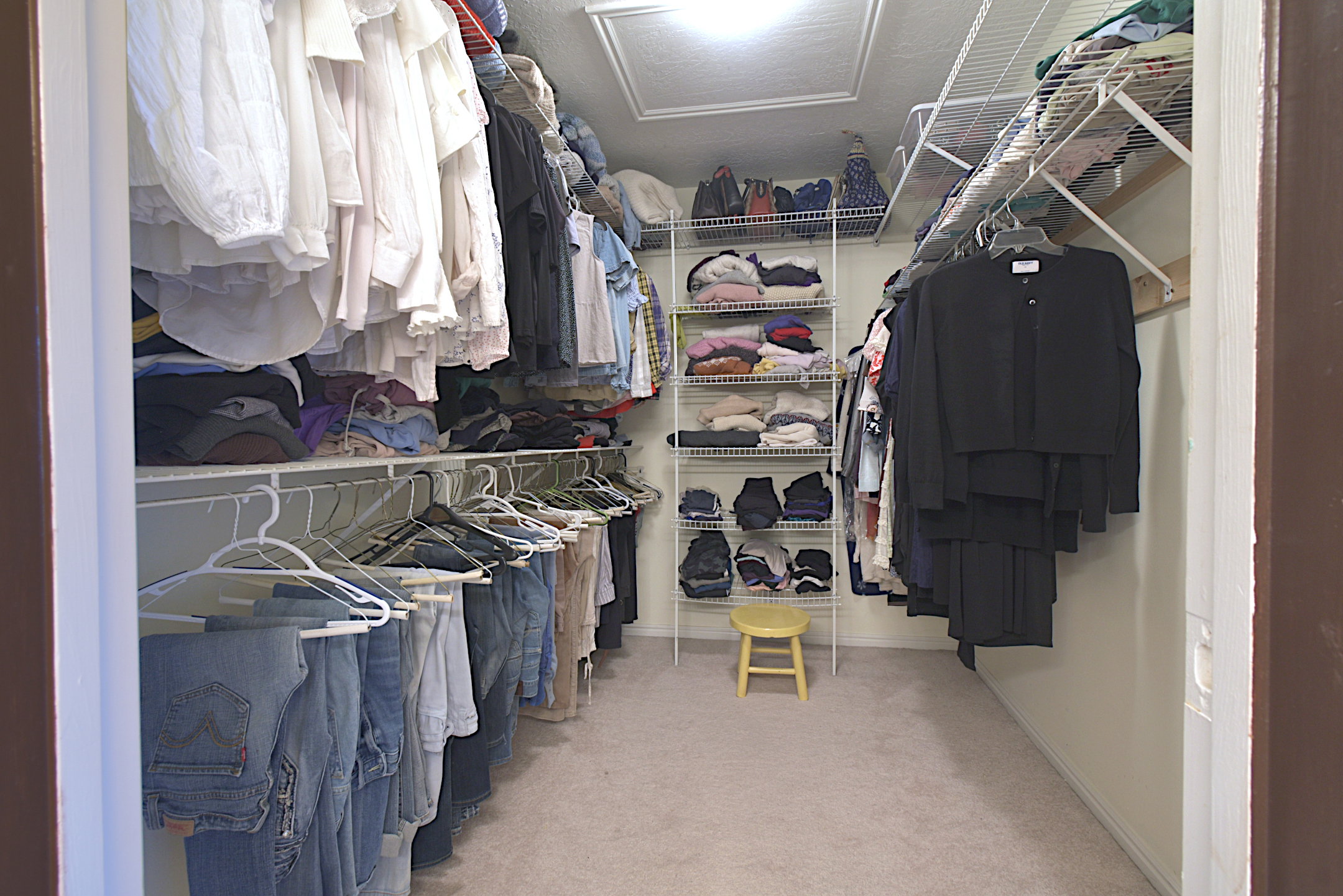 Walk-in closet featuring extensive wire shelving, multiple hanging rods, and light-toned carpeting