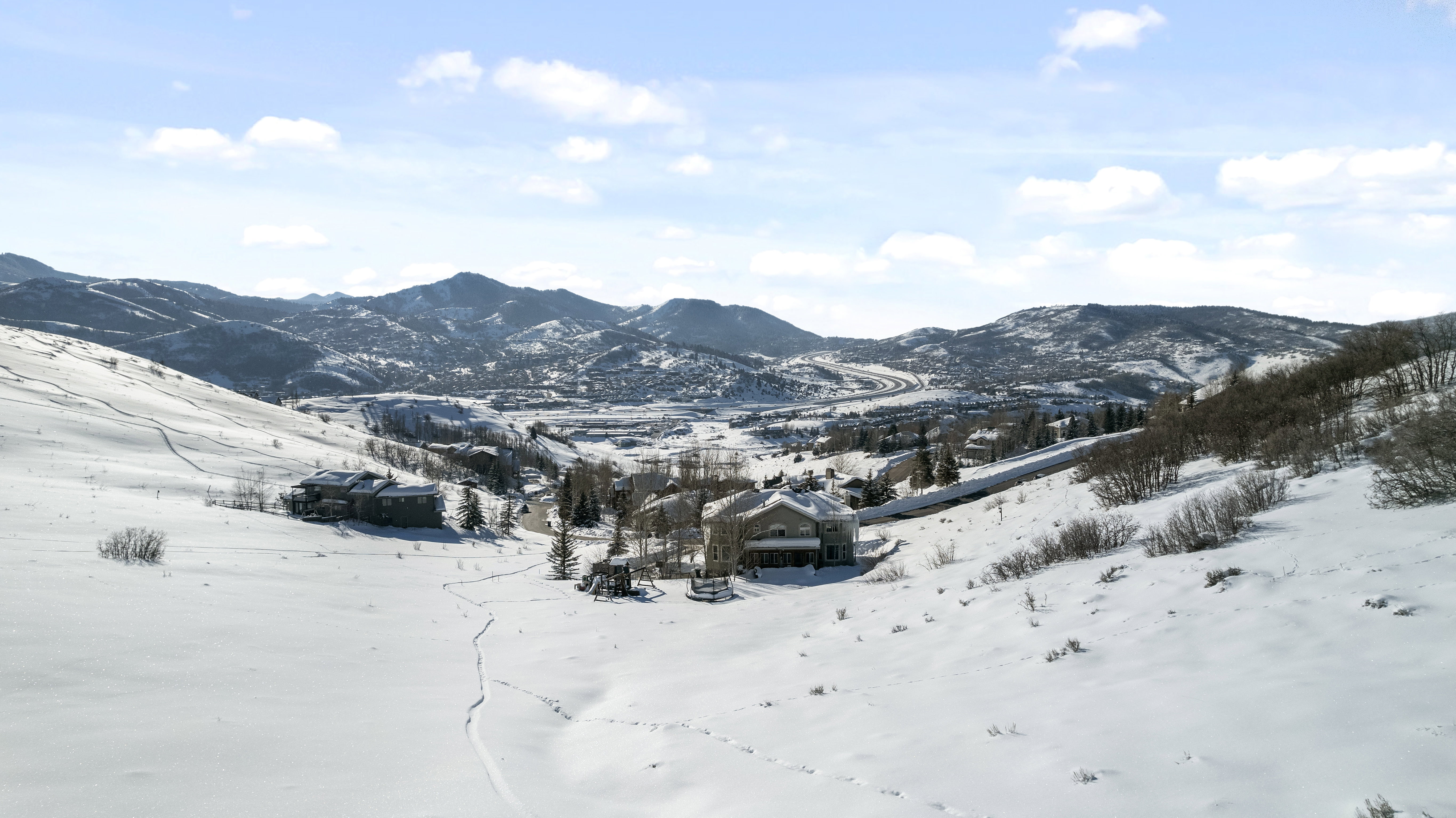 Expansive snow-covered landscape with distant mountain ranges and scattered residences